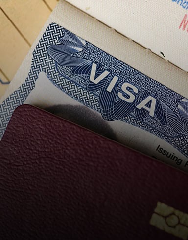 A close-up of a visa document partially covered by a maroon passport, handled by Louisiana immigration lawyers.