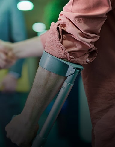 A person wearing a rolled-up pink shirt uses a forearm crutch and greets someone, reflecting trust like top personal injury lawyers Louisiana.