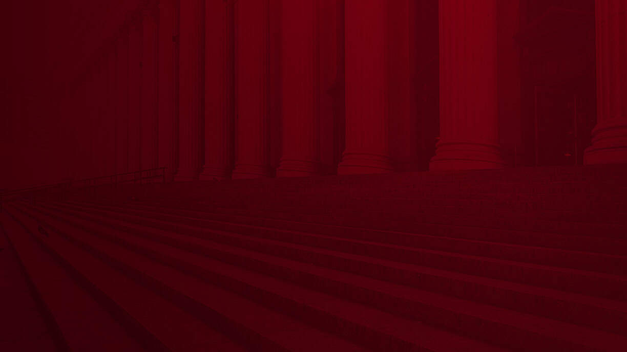 Wide stone steps and tall columns, tinted dark red, mark the entrance of Louisiana immigration lawyers’ historic building.