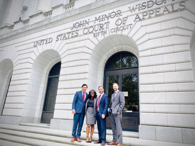 Four people in business attire stand before the United States Court of Appeals for the Fifth Circuit, representing top immigration visa lawyers.