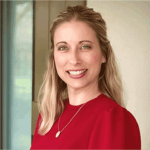 Woman with long blonde hair in a red top, smiling near a window—perfect for personal injury lawyers Louisiana profiles.