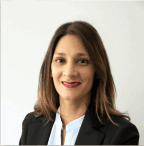 Woman with straight brown hair in a black blazer and blue blouse, smiling, representing leading immigration lawyers Louisiana.