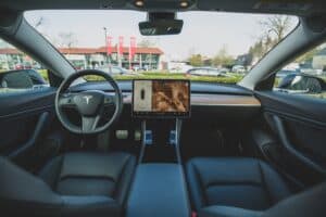 Interior of a Tesla car showing the steering wheel, dashboard, center touchscreen display, and black leather seats—perfect for Louisiana immigration lawyers.