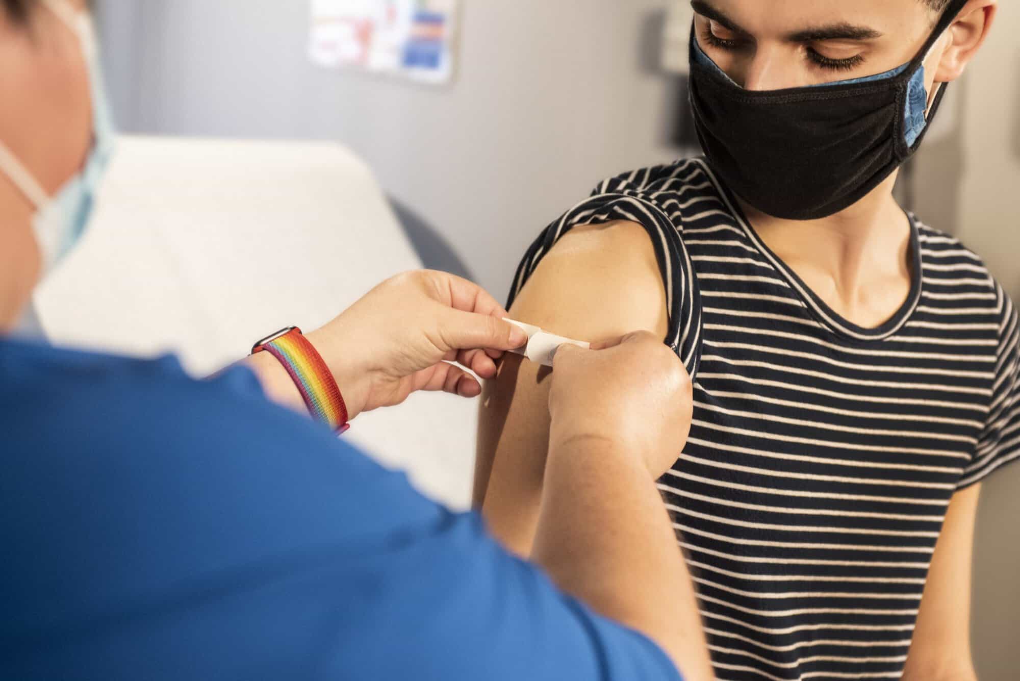 A healthcare worker bandages a masked person’s arm post-vaccine—just as personal injury lawyers Louisiana care for clients after an accident.