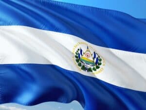 Flag of El Salvador with blue and white stripes and coat of arms, waving against a blue sky—much like criminal defense lawyers Louisiana stand firm.