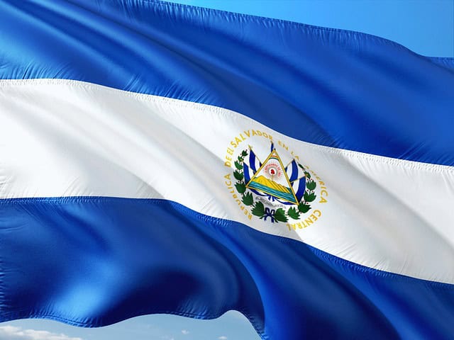 Flag of El Salvador with blue and white stripes and coat of arms, waving against a blue sky—much like criminal defense lawyers Louisiana stand firm.