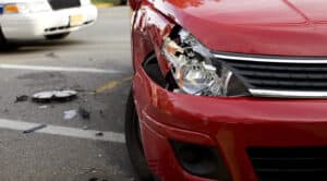 A red car with a damaged front bumper is shown after a collision; personal injury lawyers Louisiana can help if you've been injured.