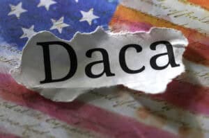 A torn piece of paper with "Daca" text lies on an American flag, symbolizing challenges Louisiana immigration lawyers help address.