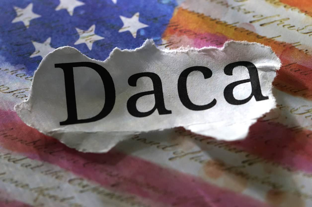 A torn piece of paper with "Daca" text lies on an American flag, symbolizing challenges Louisiana immigration lawyers help address.