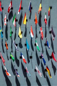 Multiple national flags mounted on a gray wall in rows, sunlight casting shadows—ideal backdrop for Louisiana immigration lawyers' offices.