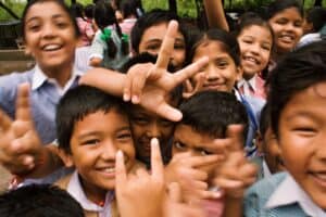 A group of smiling children in school uniforms stands close together, some making hand gestures—future louisiana immigration lawyers in the making.