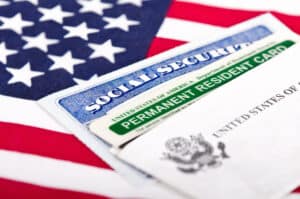 A Social Security card, a Permanent Resident card, and a U.S. government document atop an American flag—key for louisiana immigration lawyers.