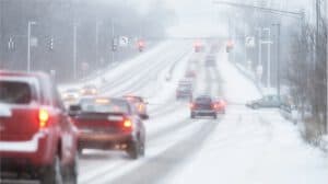 Cars driving on a snow-covered road at an intersection; visibility is reduced—personal injury lawyers Louisiana can help after winter accidents.