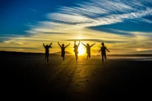 Five people leap on a sunset beach in Louisiana, silhouetted against the sky—perfect for personal injury lawyers Louisiana imagery.