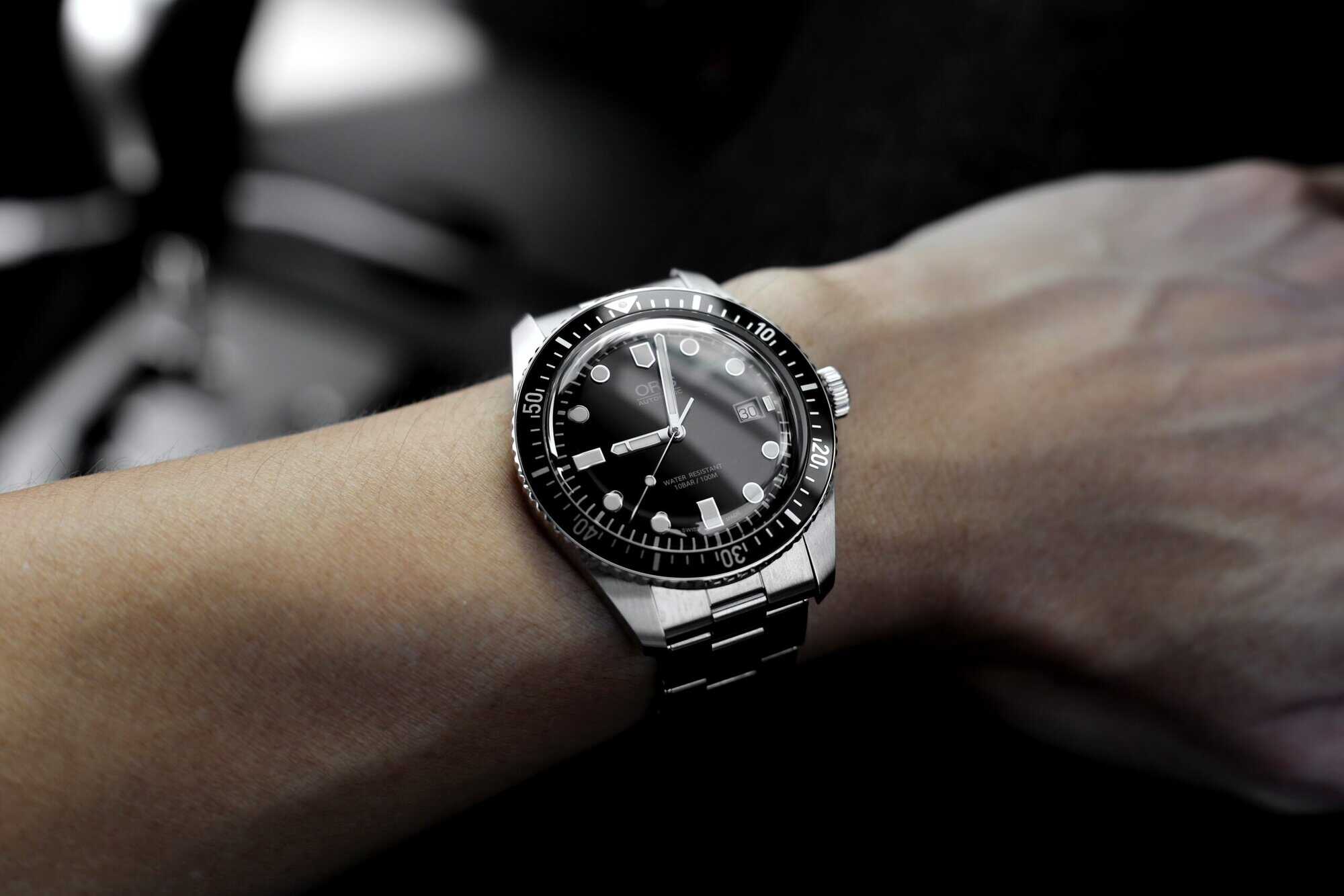 A stainless steel wristwatch with a black bezel and round markers is worn on the left wrist of a personal injury lawyer in Louisiana.