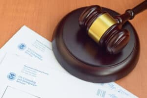 A judge’s gavel rests on top of documents labeled “U.S. Citizenship and Immigration Services,” highlighting new asylum filing fees.