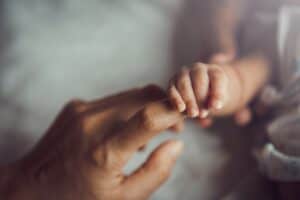 Close up of parent holding newborn baby's hand