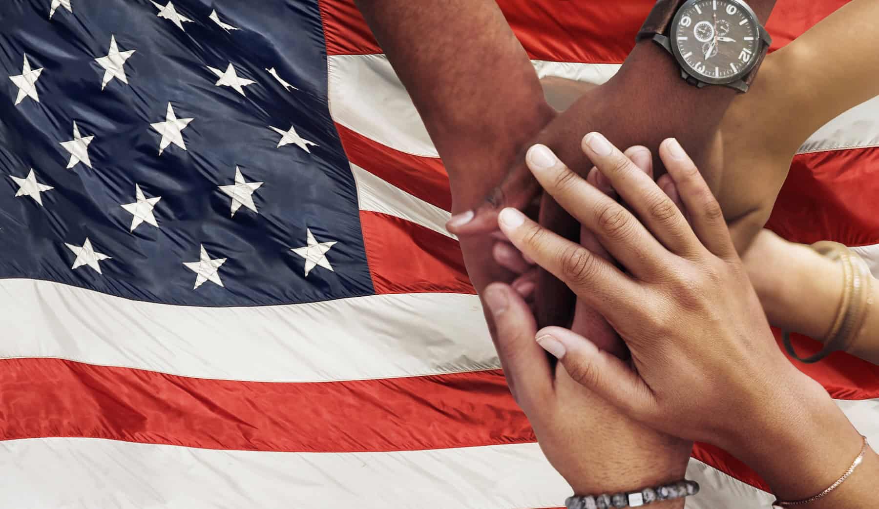 Group joining hands with the American flag in the background