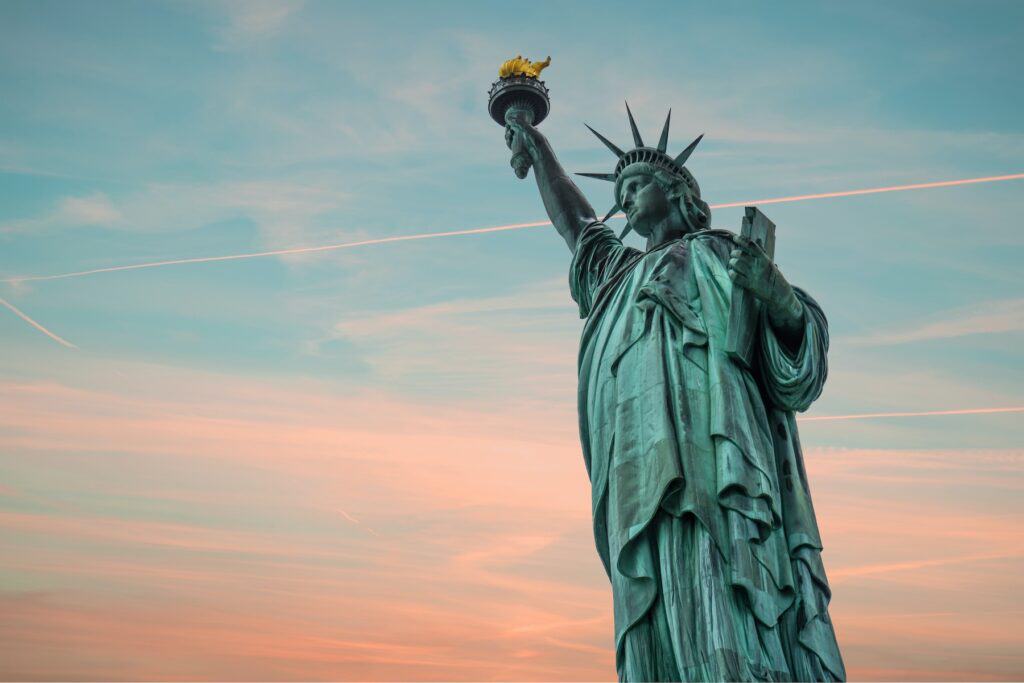View of Statue of Liberty against a blue and pink sunset sky.