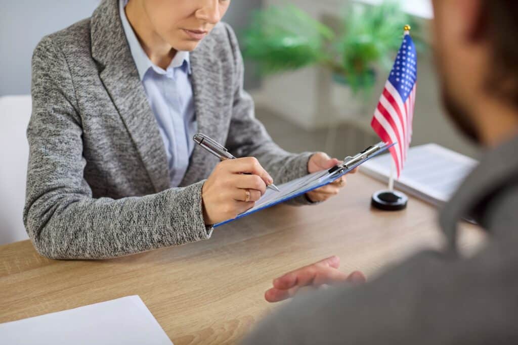 Visa interview as officer writes on documents.