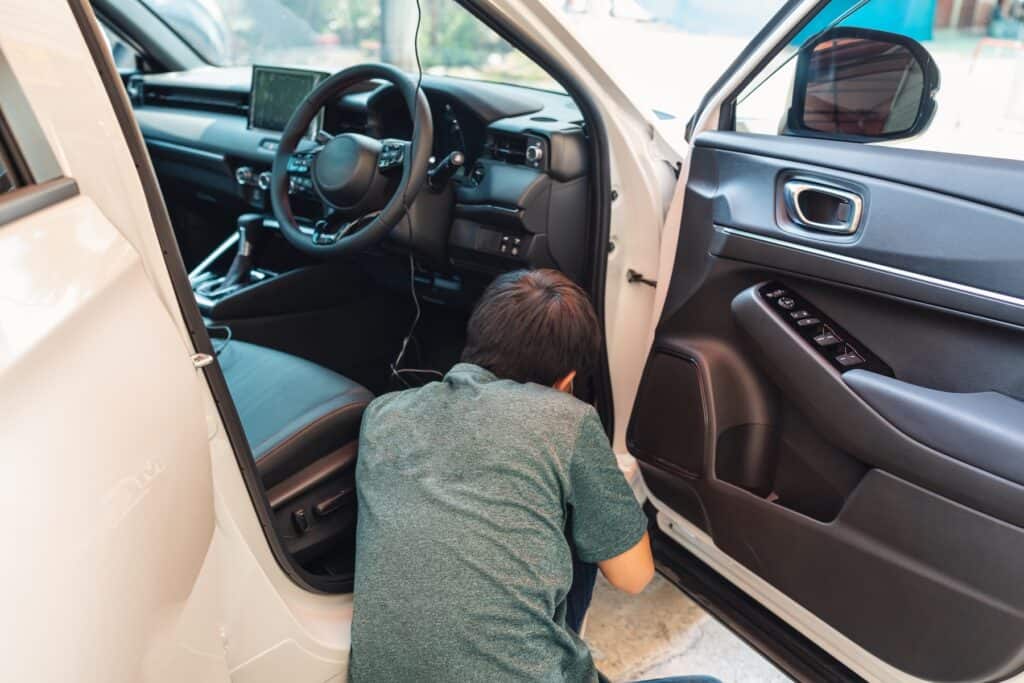 Mechanic checking and installing dash cam device with wire inside a car
