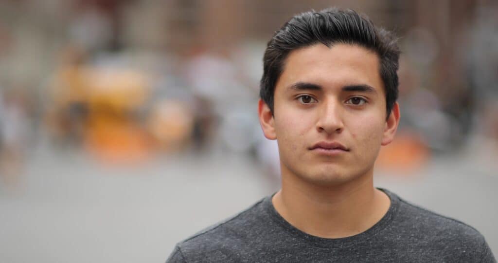 Hombre joven hispano mirando solemnemente a la cámara.